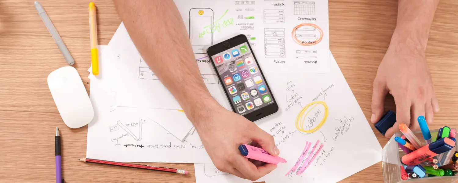 person at a desk using multi-coloured pens and sheets of paper to make a content strategy framework